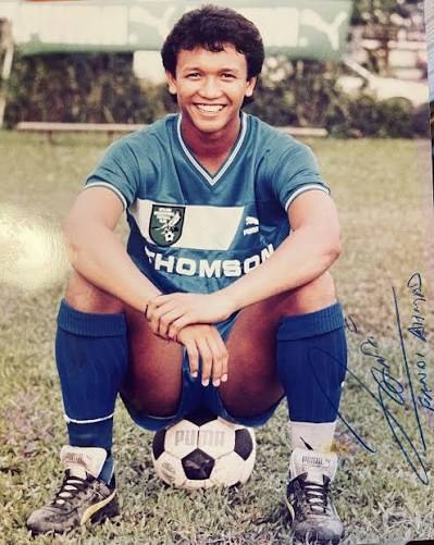 Fandi Ahmad crouching on a football in the green kit of FC Groningen, smiling, in a signed publicity photograph