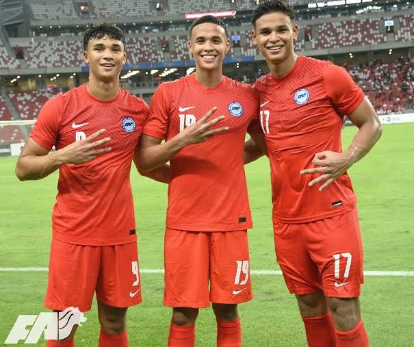 Ikhsan, Ilhan and Irfan Fandi in Singapore's red kit at the National Stadium, each making a three-fingered gesture