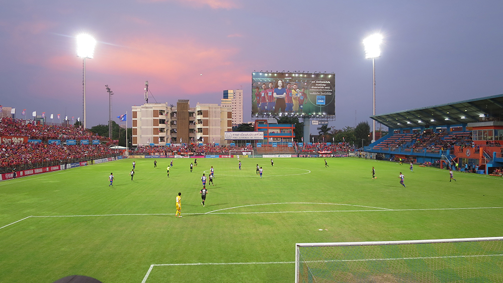 A match under floodlights at PAT Stadium in Khlong Toei at dusk, with the stands full