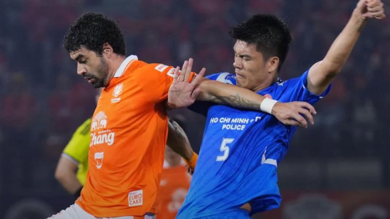 A Ratchaburi player in orange holds off Công An Hồ Chí Minh City's number 5, in blue, during their 1–1 draw