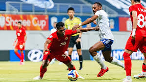 Công An Hà Nội’s number 38, in red, shields the ball from a Lion City Sailors player in white
