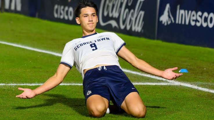 Mitchell Baker celebrates a goal for Georgetown on his knees, arms out
